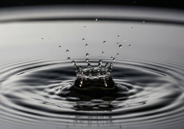 Bir su damlası çarpışmasının yüksek hızda makro görüntüsü sıçrayan bir taç, soyut bir taç ve akışkan hareket konsepti yaratır.