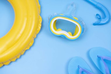 Renkli halka yüzen sarı arka plan ile Flip-flop ve şnorkelli yüzme maskesi