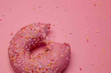 Isırılmış pembe donut beyaz arka plan üzerinde pembe arka plan üzerinde renkli şeker taltalları ile izole.