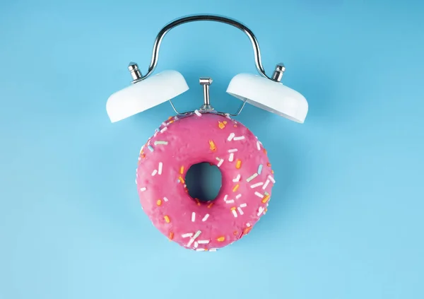 Donuts mavi arka plan üzerinde çalar saat alarmı ile sır. Donut çalar saat.