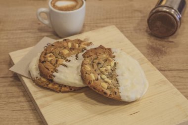 Tahtaya badem ve beyaz çikolata parçacıklı kurabiyeler serpiştirin. Ahşap arkaplan.