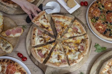 Carbonara 'da pizza topluyorum. Tahta arka planda çeşitli pizzalar bulunan pizza masası..