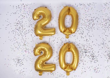 2020 adet hayal kırıklığına uğramış altın balon beyaz arka planda renkli konfeti ile izole edilmiş. Mutlu yıllar 2020 tatili.