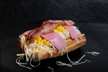 Siyah arka planda rendelenmiş peynirli, mısırlı, pastırmalı ve tatlı jambonlu Venezuela sosislisi.