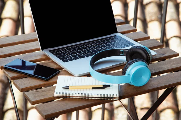 Isolated image of terrace table with portable headphones and notepad. I work from the terrace at home