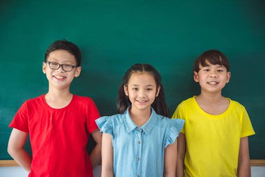 Yazı tahtası ve gülümseme önünde üç Asya shoolkid ayakta