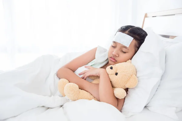年轻的亚洲病态女孩与泰迪熊睡在额头上的凉爽凝胶 — 图库照片