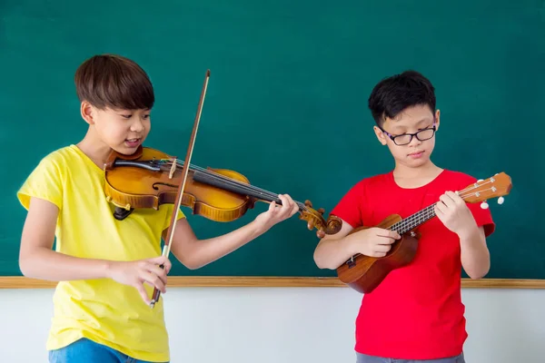 Young boys playing music instrument in classroom