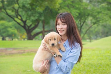 Onu küçük köpek Park ile gülümseyen güzel Asyalı kız