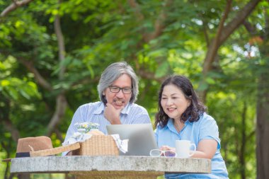 Mutlu Asya emekli çift parkta dizüstü bilgisayar kullanan