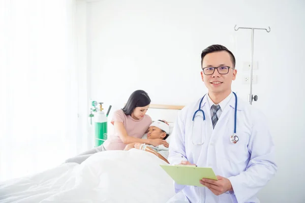 Guapo Asiático Macho Doctor Sonriendo Cámara Con Paciente Familia Fondo —  Fotos de Stock