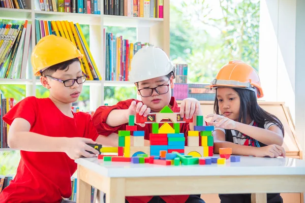 人のアジア子供ヘルメットを着用し 学校図書館建設木材ブロックを再生 — ストック写真