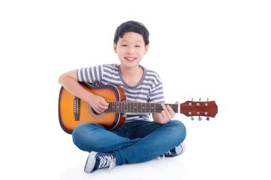 Genç Asyalı çocuk gitar ve gülümsüyor beyaz arka plan üzerinde oynama