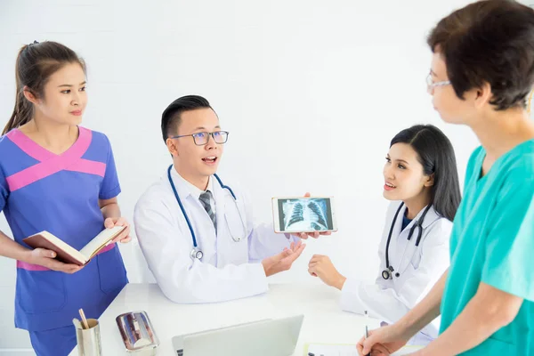 Group of doctors and nurses discuss and looking patient\'s x-ray result