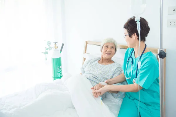 亚裔女性病人微笑着与护士谁来看望她在床上 — 图库照片