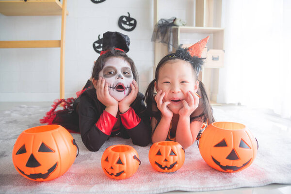 Little asian girls lying and smile in room decorated for Halloween day