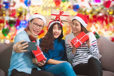 Asya Gençler, bir adam ve iki kadın tarafından Noel partisi cep telefonu fotoğraf çekme.