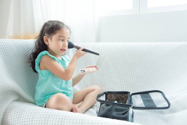 Şirin Asyalı kızı koltukta oturan ve yüzünde makyaj