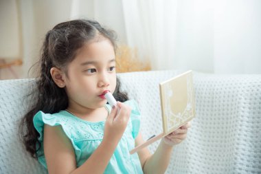 Şirin Asyalı kızı koltukta oturan ve ruj dudakları üzerinde koyarak