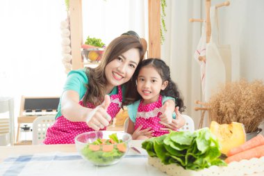 Güzel Asyalı anne ve pembe giyen kızı yemek kahvaltı önlük