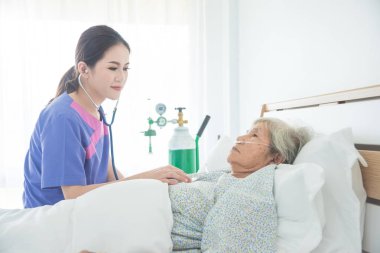 Üst düzey Bayan hasta Doktor muayene ederken yatakta stetoskop tarafından yalan