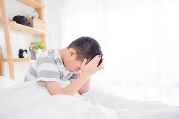 Unga asiatiska pojke som vaknar med huvudvärk — Stockfoto