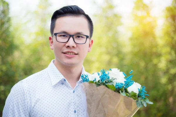 彼のガール フレンドを与えるため花を持って若い男性の肖像画 — ストック写真