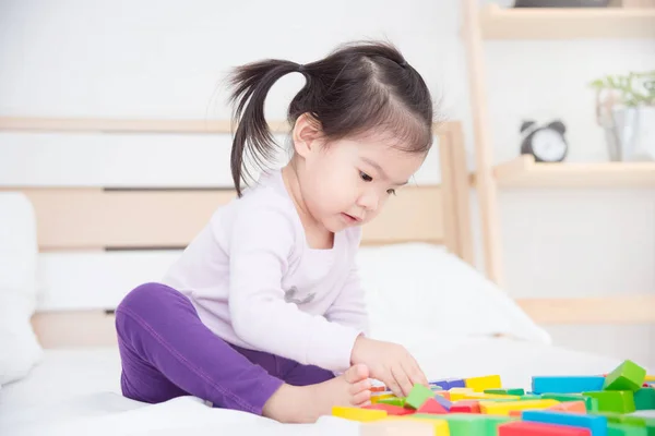 Malá Asijská dívka sedící na posteli a hrající hračky — Stock fotografie