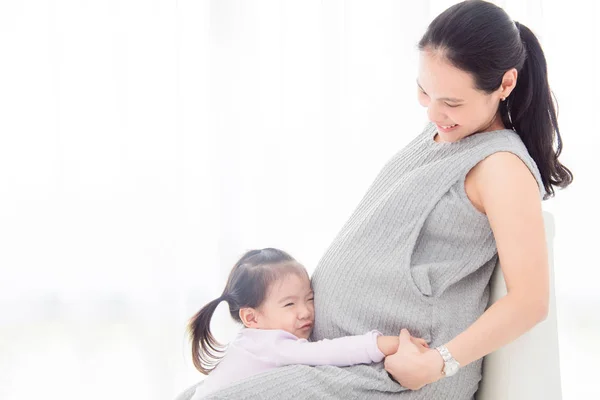 Pequeña chica asiática abrazando y escuchando sonido desde el vientre de su madre —  Fotos de Stock
