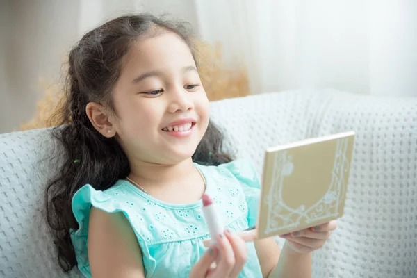 Leuke Aziatische dochter lachend na de invoering van lippenstift op haar lippen — Stockfoto