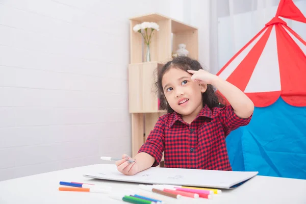 Pouco asiático menina pensando e desenho de imagem na mesa — Fotografia de Stock