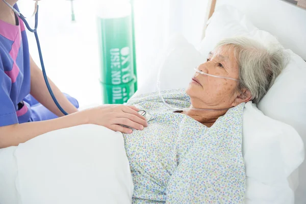 听诊器医生检查时躺在床上的老年女性 — 图库照片
