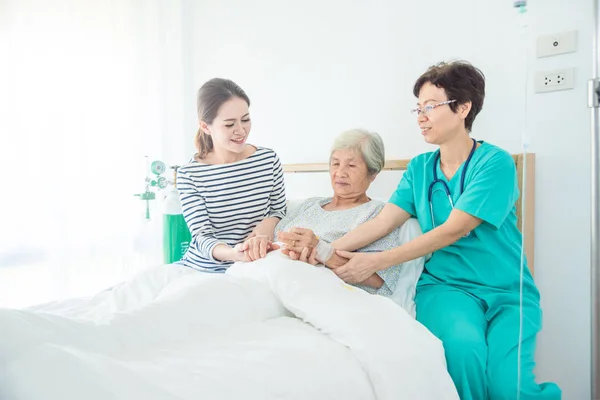医者の家族と一緒にベッドで高齢女性患者の嘘話 — ストック写真