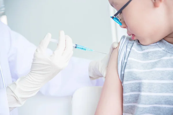 在诊所给一个男孩接种疫苗的医生. — 图库照片