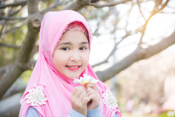 Bir ağacın altında duran ve beyaz çiçek tutan Müslüman kız — Stok fotoğraf