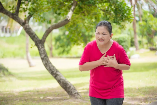 Mujer anciana que sufre de un ataque al corazón mientras hace ejercicio en el parque —  Fotos de Stock