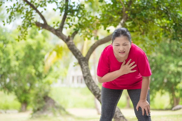 Пожилая женщина, страдающая от сердечного приступа во время физических упражнений в парке — стоковое фото