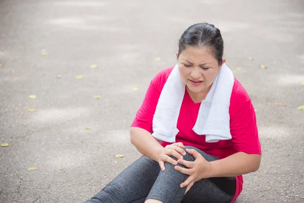 Літня жінка страждає від болю в колінах під час бігу в парку — стокове фото