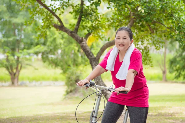 美丽的老年妇女骑自行车在公园锻炼 — 图库照片
