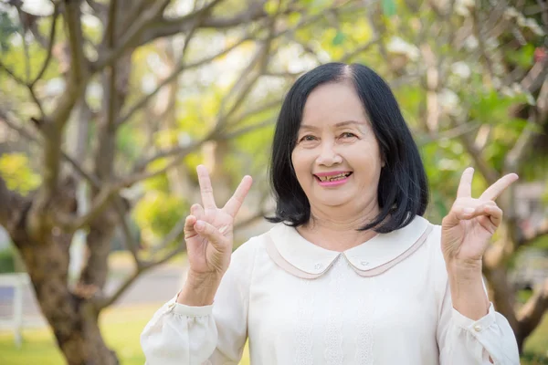 Mooie Senior vrouw staande en glimlachend in Park — Stockfoto