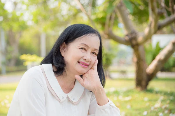 Mooie Senior vrouw zittend en glimlachend in Park — Stockfoto
