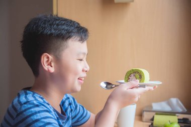 yeşil çay rulo pasta tutan çocuk ve gülümsüyor