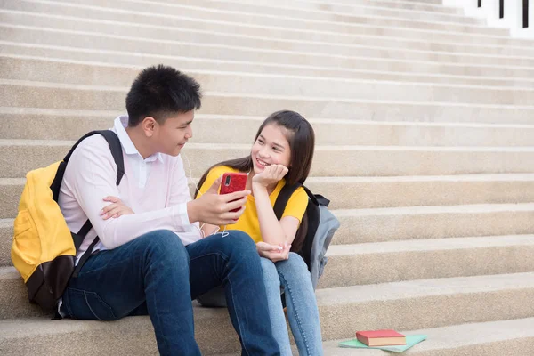 Genç erkek ve kız okulda merdiven üzerinde oturan ve müzik dinlerken — Stok fotoğraf