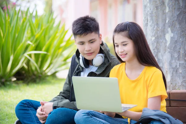 Genç erkek ve kız parkta oturan ve dizüstü bilgisayar kullanarak — Stok fotoğraf