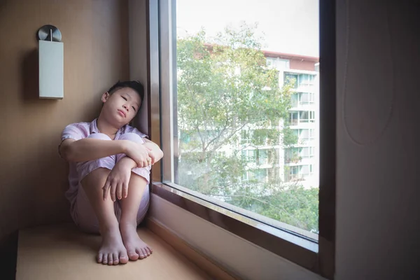 Sad boy sitting near by the window alone at home — Stock Photo, Image