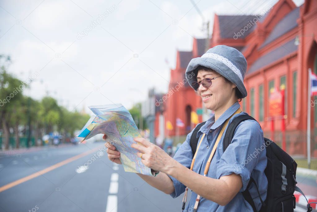 Senior woman tourist holding a paper map traveling in Thailand