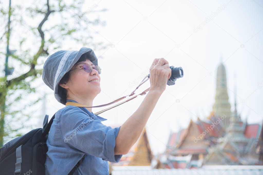 Senior woman tourist taking photo in front of grand palace