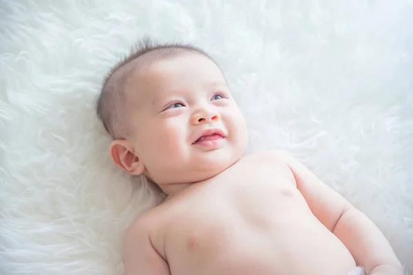 Bebê deitado na cama e sorri — Fotografia de Stock