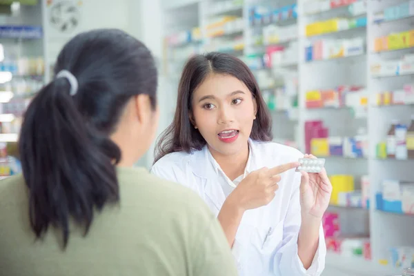 Lékárník vysvětlující léky pacientovi v obchodě s drogami — Stock fotografie