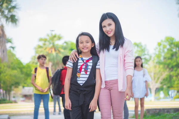 Parent and schoolgirl of primary school standing together and smile — Stock Photo, Image